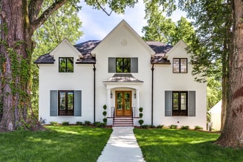 Remodeled home exterior, traditional style. Painted white brick, wood french front doors, large windows.