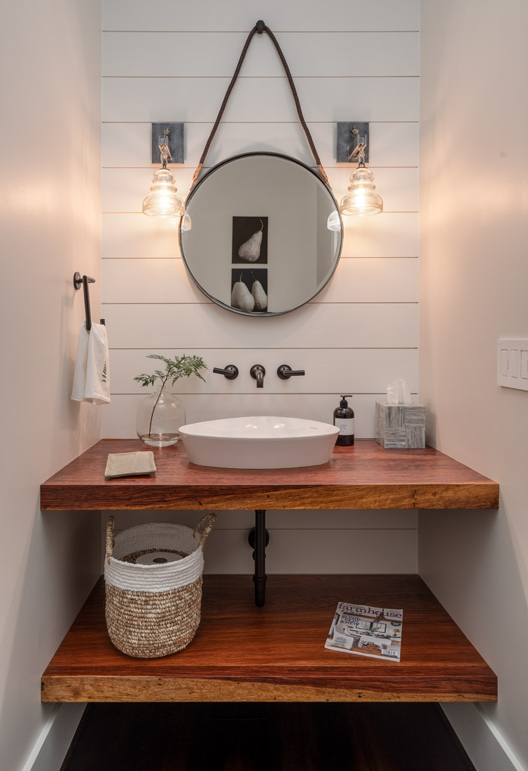Stylish powder room remodel in Greensboro, NC by Wolfe Homes with rustic wood vanity and round mirror