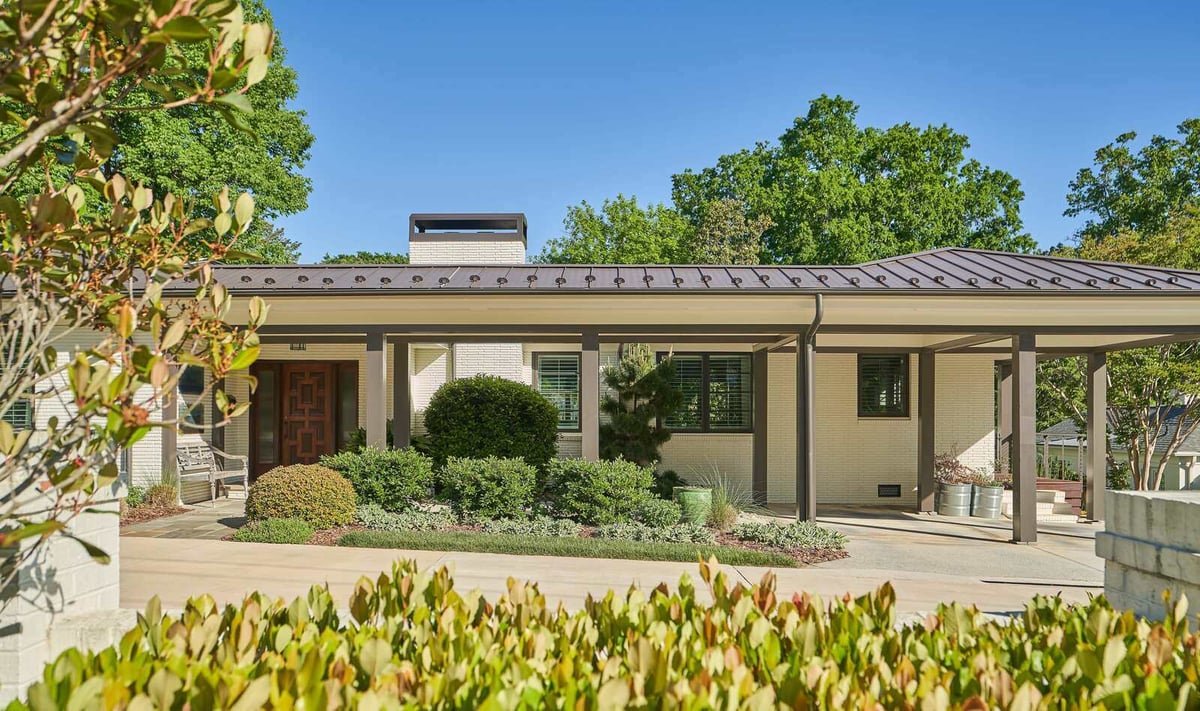 Modern front entrance surrounded by manicured landscaping and a sleek metal roof