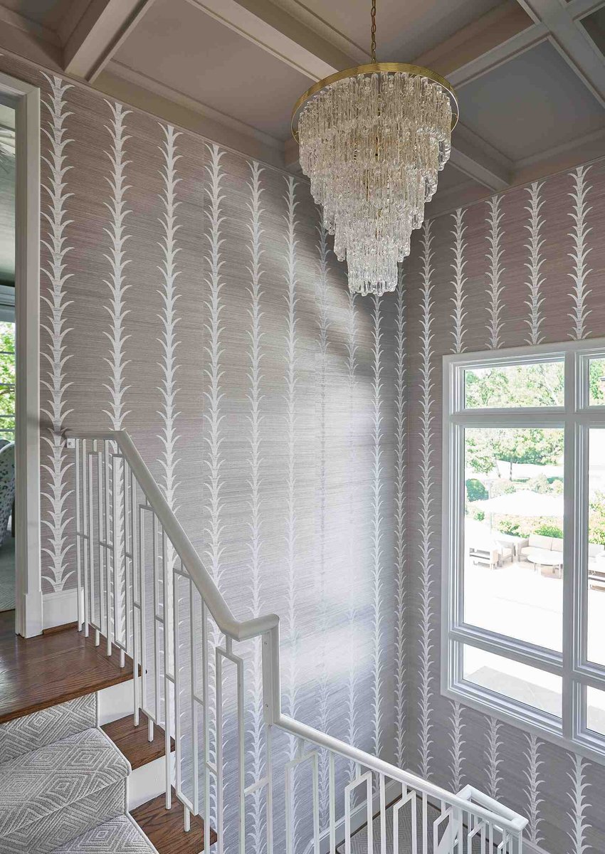 Staircase with a statement crystal chandelier and decorative wallpaper