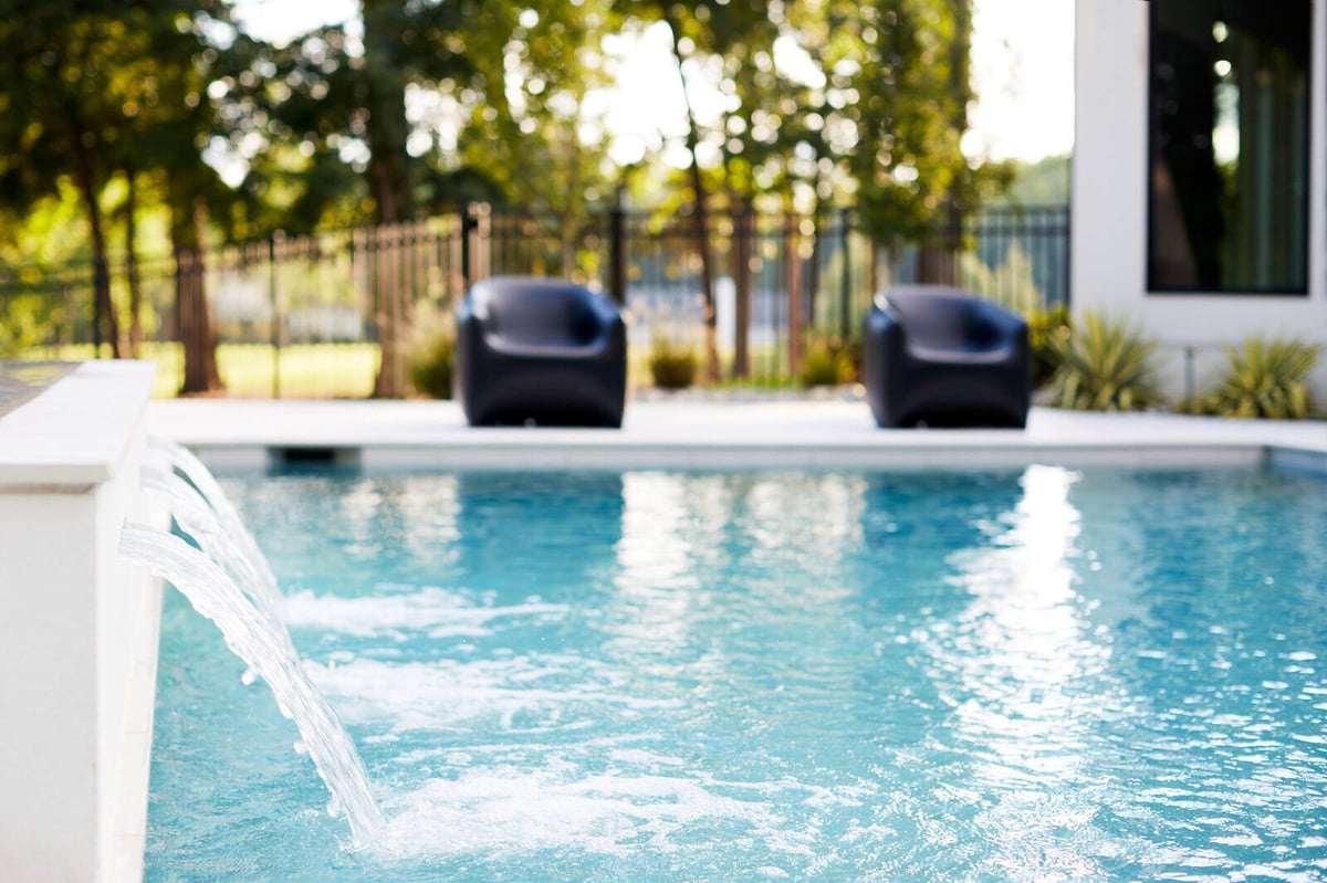 Backyard poolside area with water features and outdoor seating, designed by Allen & James in Gaston County