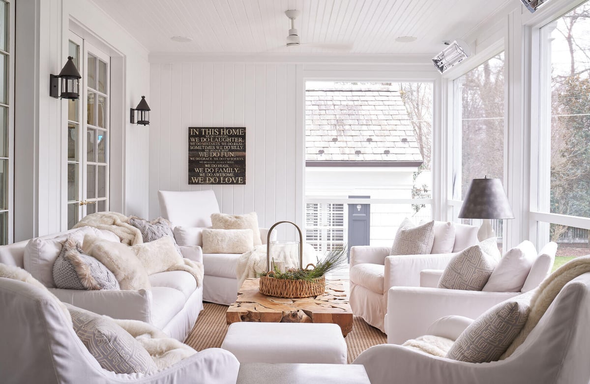 Serene sunroom with white seating and rustic wood table in a custom remodel by Wolfe Homes, Greensboro, NC