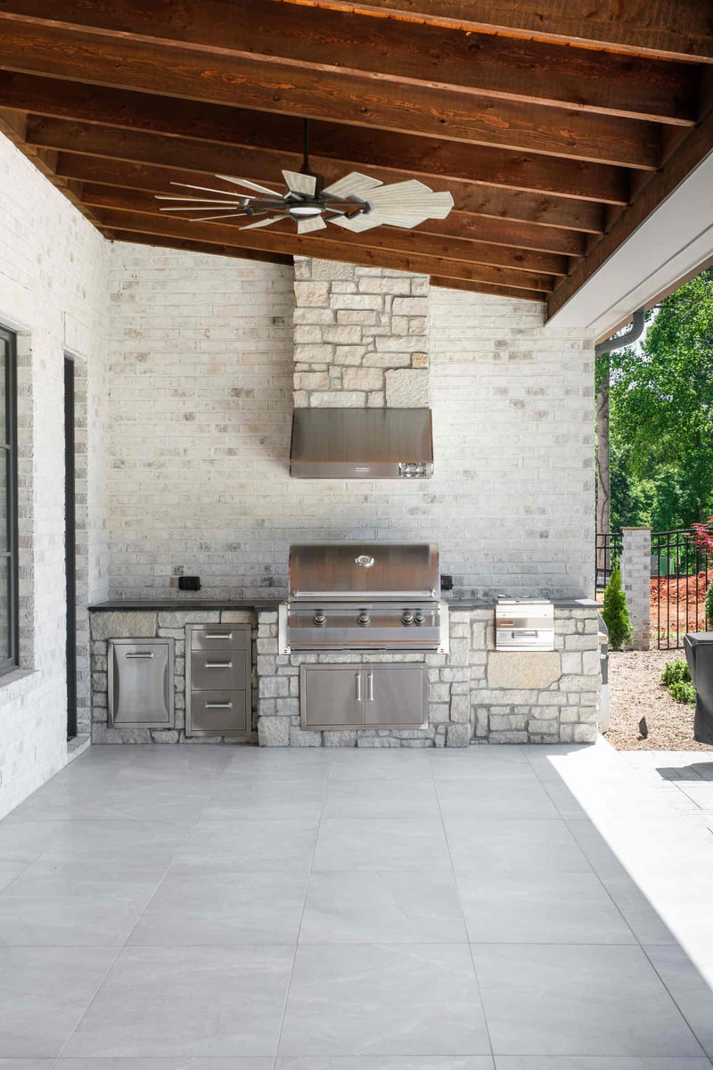 Outdoor kitchen with stainless steel grill and stone accents in a custom Greensboro home by Wolfe Homes