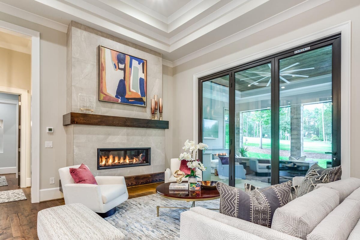 Cozy living room with fireplace and large windows in a custom Greensboro home by Wolfe Homes