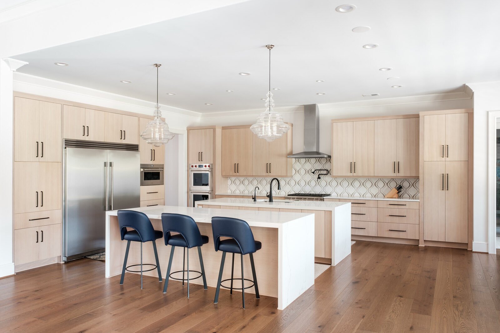 Modern kitchen with light wood cabinetry and island seating by Wolfe Homes in Greensboro, NC